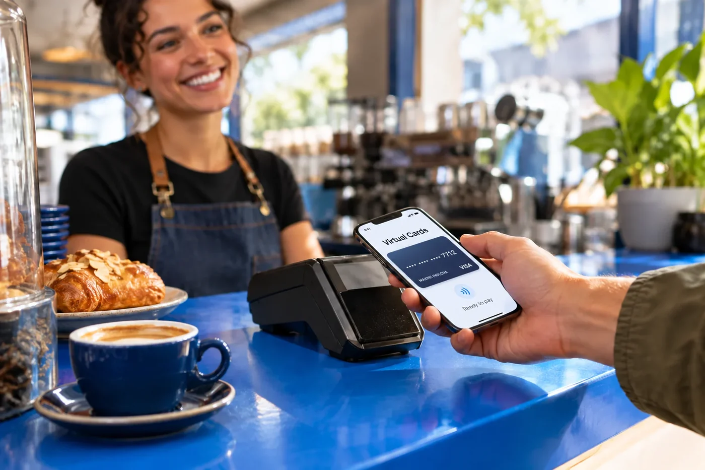 Cafe customer holding a smartphone beside a payment terminal